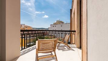 A balcony with two wicker chairs and a black metal railing.