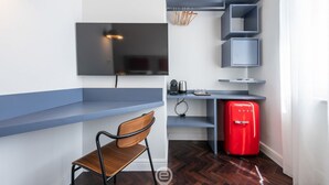 Une cuisine compacte équipée d’un téléviseur encastré, d’un réfrigérateur rouge et d’une chaise en bois.