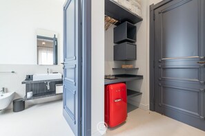 A modern bathroom with a white sink, dark vanity, and a red refrigerator. - Verso Suites Cagliari (Cagliari)