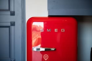 A red vintage-style refrigerator with the brand name "SMEG" on the front.