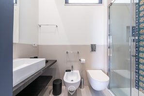 A modern bathroom with a bidet, toilet, and a glass-enclosed shower.