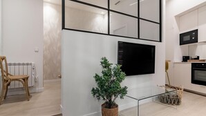 A modern kitchen with a flat-screen TV mounted on the wall, a built-in microwave, and a stove. - Charming Almudena I - (Madrid)