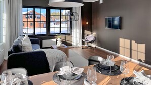 A modern living room with a dining area set for a meal.