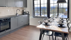 A modern kitchen with grey cabinets, a built-in oven, and a dining area with a wooden table set for six.