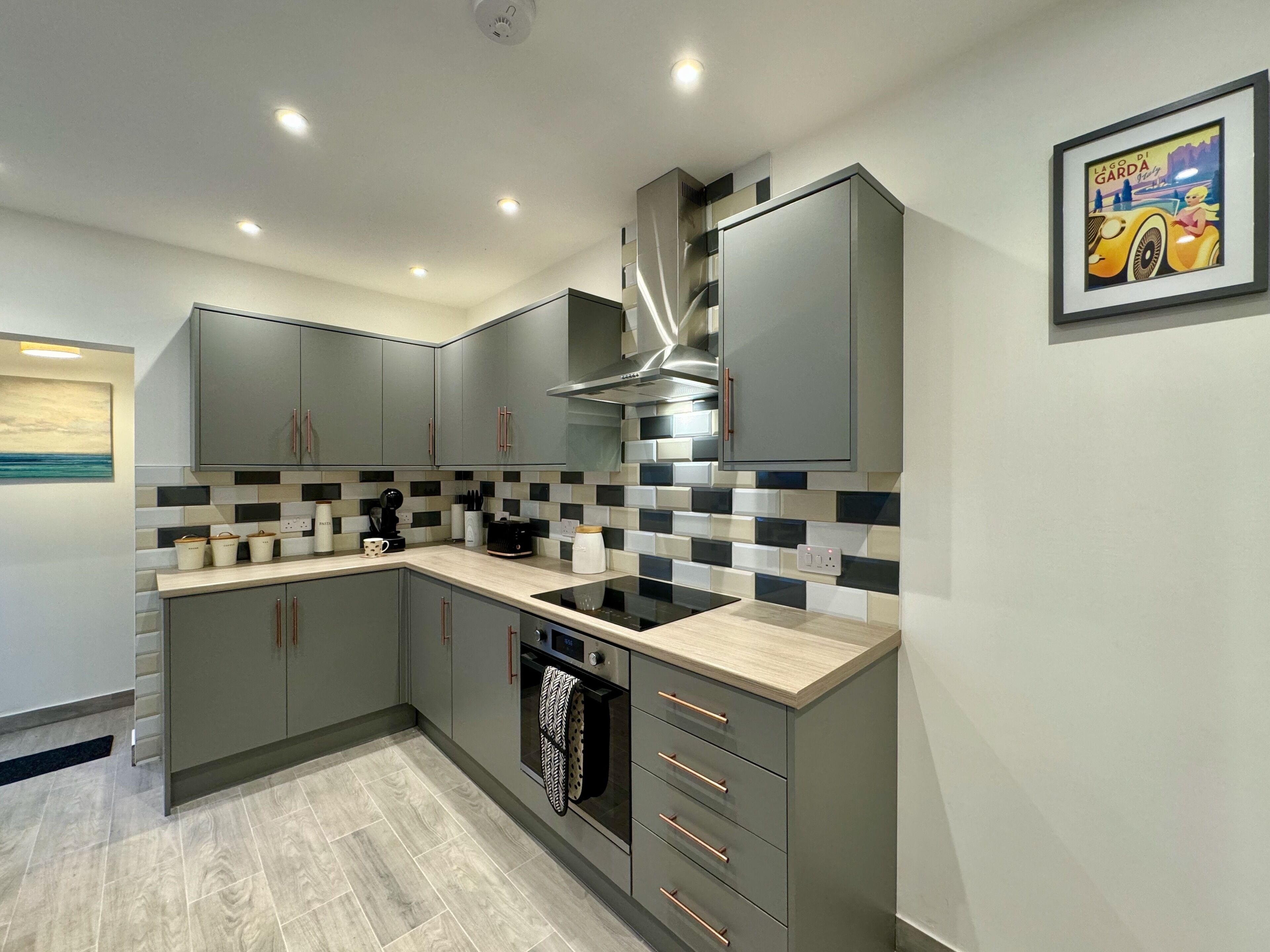 A modern kitchen with grey cabinets, a black stove, and a tiled backsplash.