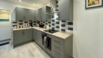 A modern kitchen with grey cabinets, a black stove, and a tiled backsplash.