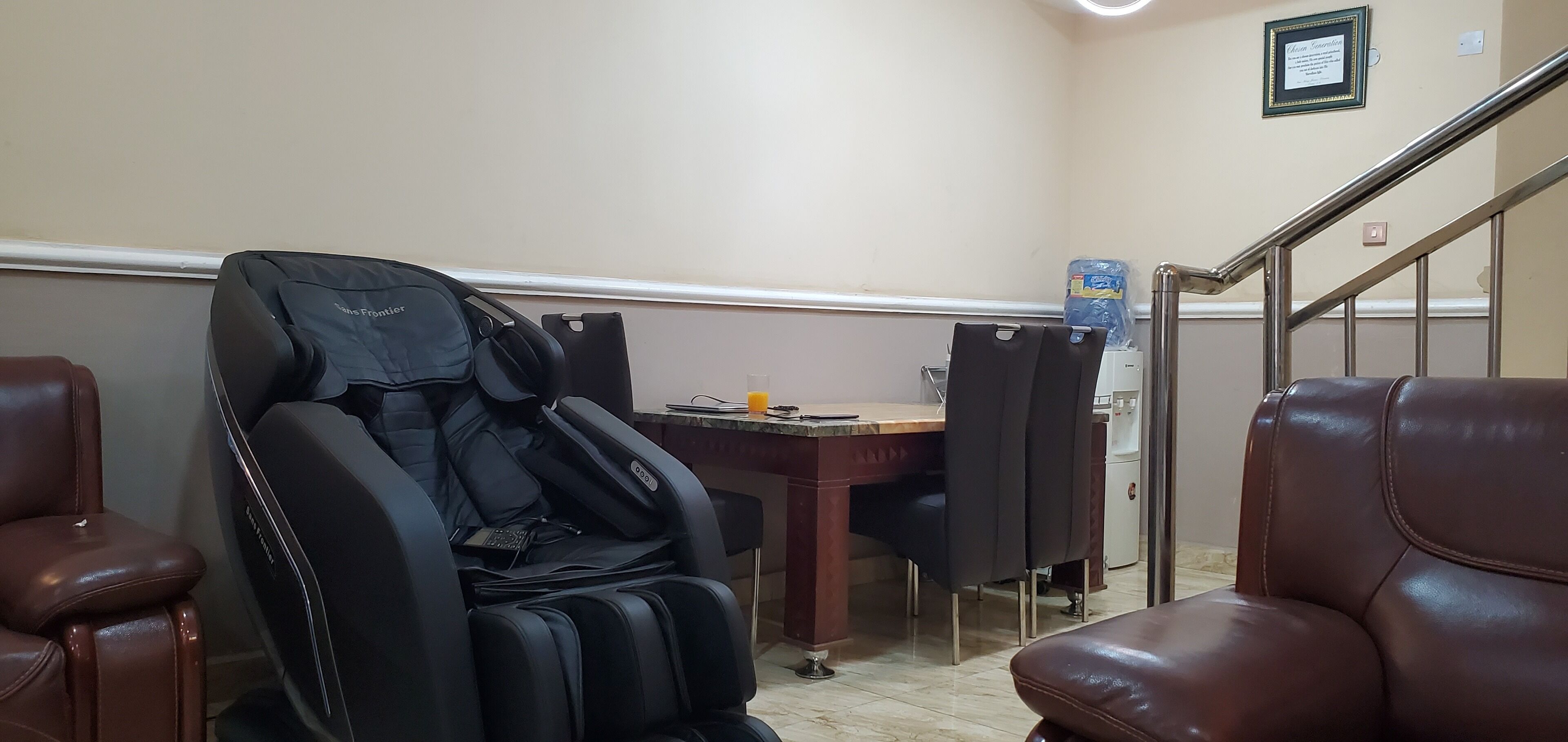 A massage chair, a desk with a chair, a water dispenser, and a staircase.