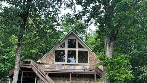 Une cabane en bois à deux étages, dotée d’un balcon et entourée d’arbres.