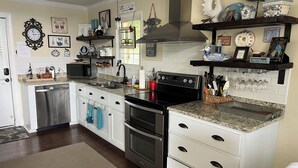 Une cuisine avec des meubles blancs, des appareils en acier inoxydable et des objets décoratifs disposés sur des étagères.