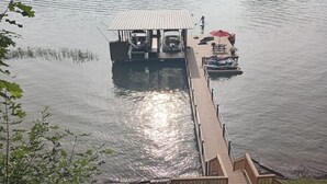 Une jetée en bois s’avance sur un lac paisible, avec des bateaux amarrés à son extrémité.