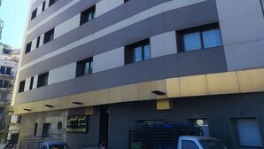 A modern hotel with a flat facade, multiple windows, and a sign indicating it is Hotel El Ghazali. - El Ghanami Hotel (Algiers)