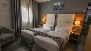 A hotel room with two beds, a chair, and a painting on the wall. - El Ghanami Hotel (Algiers)