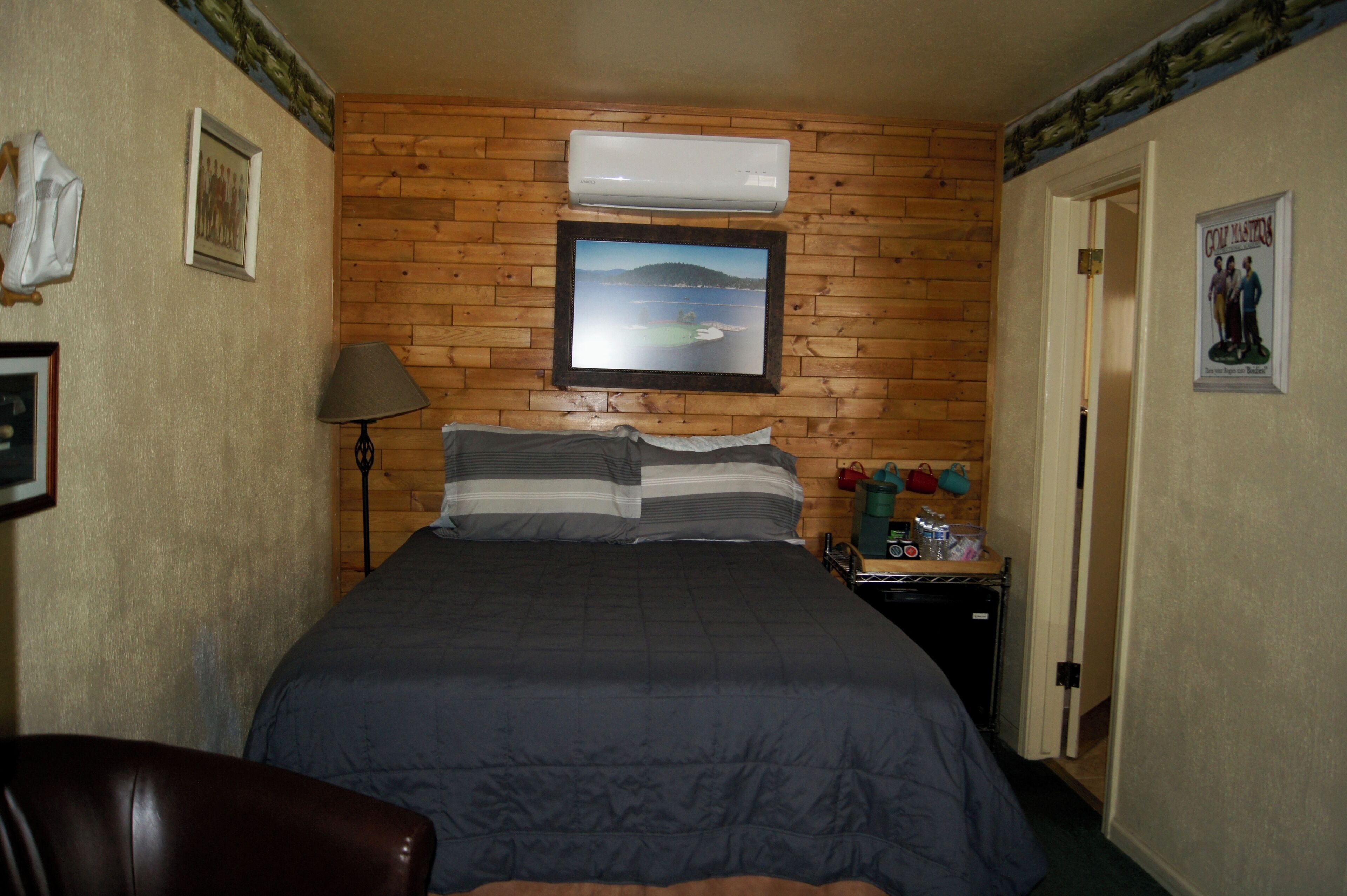 A bedroom with a bed, a nightstand, a lamp, and a poster on the wall.