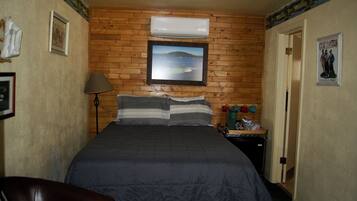 A bedroom with a bed, a nightstand, a lamp, and a poster on the wall.