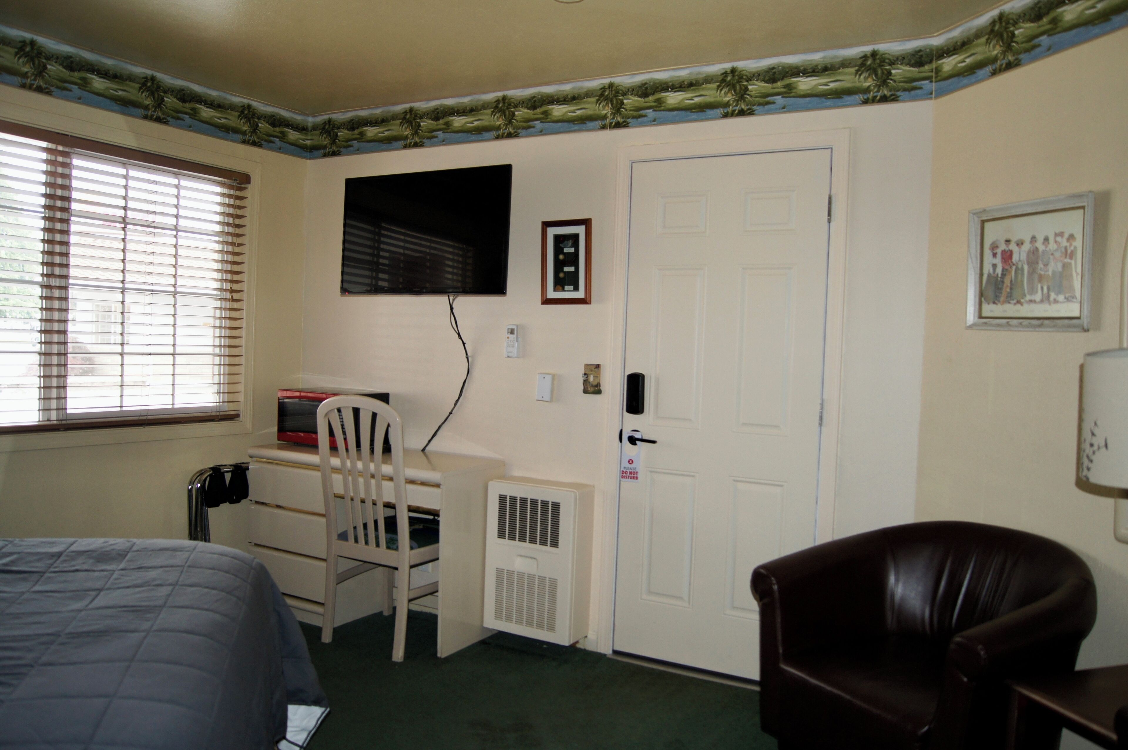 Un dormitorio con cama, escritorio, silla, radiador, puerta y ventana con persianas.