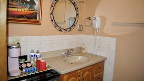 Baño con lavamanos, espejo y cafetera.