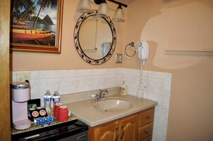 Baño con lavamanos, espejo y cafetera.