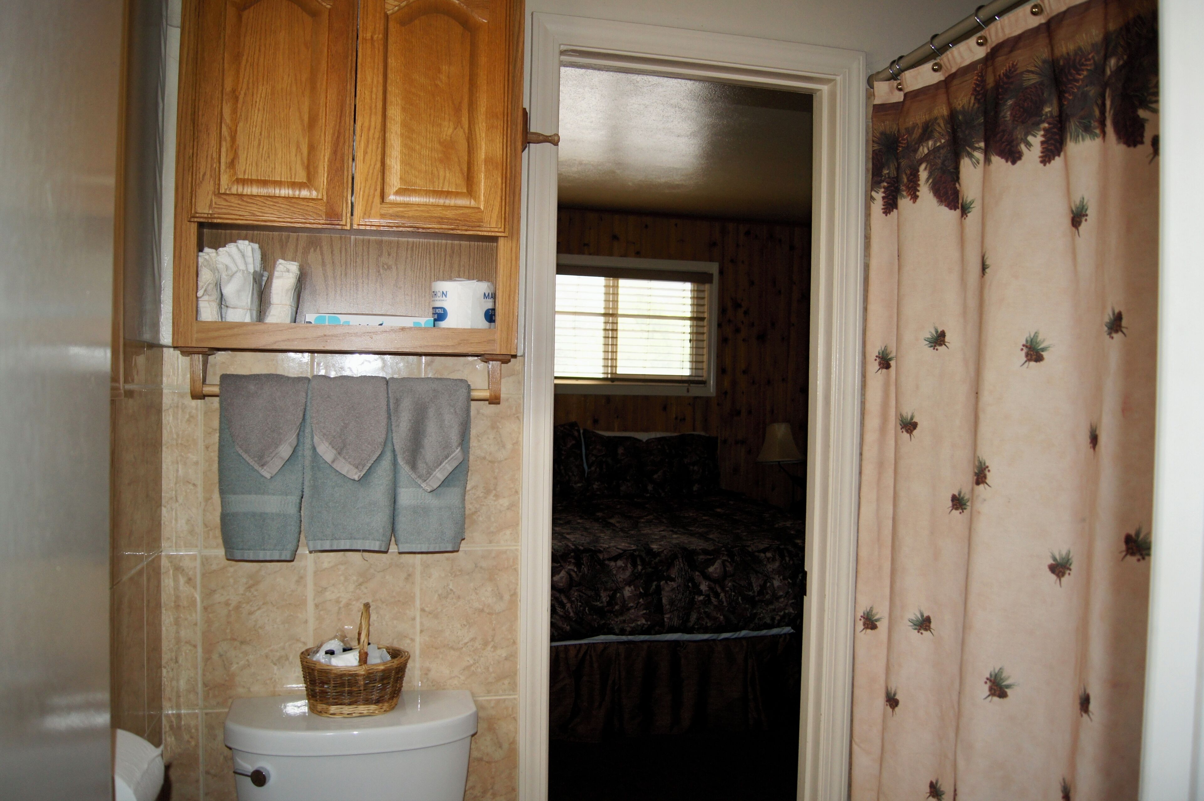 A bathroom with wooden cabinets, a toilet, and a window.