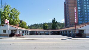 Un motel con techo rojo, un letrero y un estacionamiento.