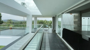 Un intérieur moderne avec une balustrade en verre, un escalier et une vue sur la verdure.