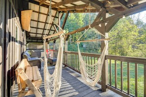 A wooden deck with a hammock, outdoor furniture, and a view of the surrounding forest. - Fireside Evenings: Red River Gorge Gem w/ Hot Tub (Campton)