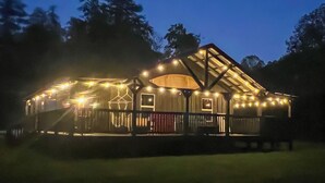 A large, well-lit building with a sloped roof, surrounded by trees. - Fireside Evenings: Red River Gorge Gem w/ Hot Tub (Campton)