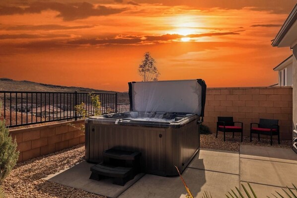 Ein Whirlpool mit Blick auf einen Sonnenuntergang, eine Backsteinmauer und zwei Stühle.