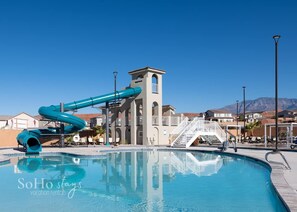 Ein Swimmingpool mit Wasserrutsche, einem Turm und blauem Himmel.