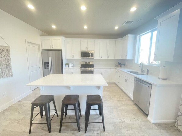 A modern kitchen with white cabinetry, a central island, and three stools.
