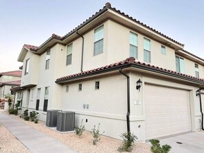 A two-story residential building with a beige facade, red-tiled roof, and a garage.
