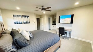 A bedroom with a large bed, a desk, and a ceiling fan.