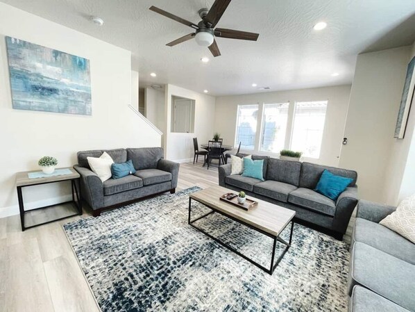 A modern living room with two grey sofas, a coffee table, and a ceiling fan.