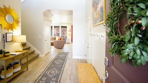 A staircase leading to a living area with a bench, a sunburst mirror, and a green plant decoration.