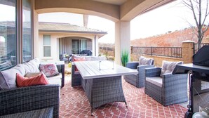 An outdoor patio with wicker furniture, a large table, and a grill.