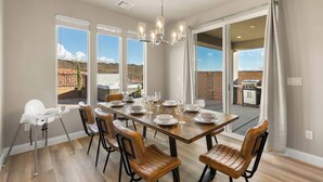 A dining area with a large table set for six, surrounded by wooden chairs, large windows, and a view of a barbecue grill outside. - Southern Utah charm. Close to St George and National Parks (Washington)