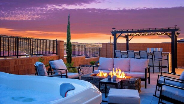 Ein Patio im Freien mit Feuerstelle, Sitzgelegenheiten und einer Pergola.