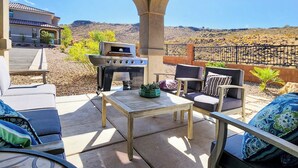 Eine Terrasse im Freien mit Grill, Sitzgelegenheit und Blick auf die Wüstenlandschaft.