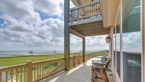 Une terrasse en bois avec des sièges extérieurs, donnant sur une pelouse et une jetée.