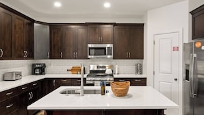 A modern kitchen with dark wood cabinets, stainless steel appliances, and a white countertop. - Southern Utah charm. Close to St George and National Parks (Washington)