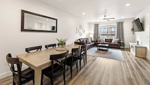 A modern living room with a wooden dining table, black chairs, a sofa, and a ceiling fan. - Southern Utah charm. Close to St George and National Parks (Washington)