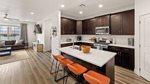 A modern kitchen with dark wood cabinets, a white countertop, and a central island with bar stools. - Southern Utah charm. Close to St George and National Parks (Washington)