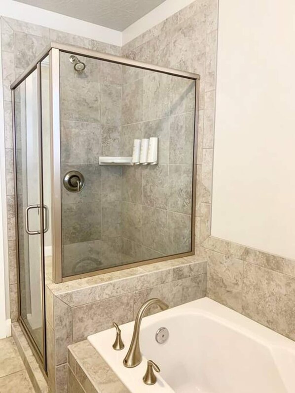Ein modernes Badezimmer mit einer begehbaren Glasdusche, einer freistehenden Badewanne und Marmorplatten an den Wänden.