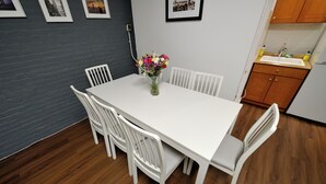 A dining area with a white table and chairs, a vase of flowers, and a kitchen in the background. - Private and Cozy  3 Bedroom in the heart of Manhattan.  (New York)