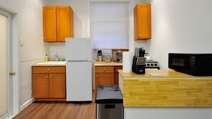 A compact kitchen with wooden cabinets, a white refrigerator, a microwave, and a trash bin. - Private and Cozy  3 Bedroom in the heart of Manhattan.  (New York)