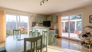 A spacious kitchen with a dining area, large windows, and a view of the backyard. - La Tara - Vue mer - Parking - Terrasse (La Plaine-sur-Mer)