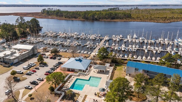 Un port de plaisance où sont amarrés de nombreux bateaux, une piscine et un bâtiment doté d’un toit bleu.