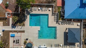 Vue aérienne d’un espace piscine comprenant plusieurs chaises longues et un coin salon abrité.