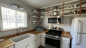A kitchen with white cabinets, a stainless steel stove, a microwave, and a refrigerator. - Cozy cottage in delightful Ahwahnee with AC, WiFi (Ahwahnee)