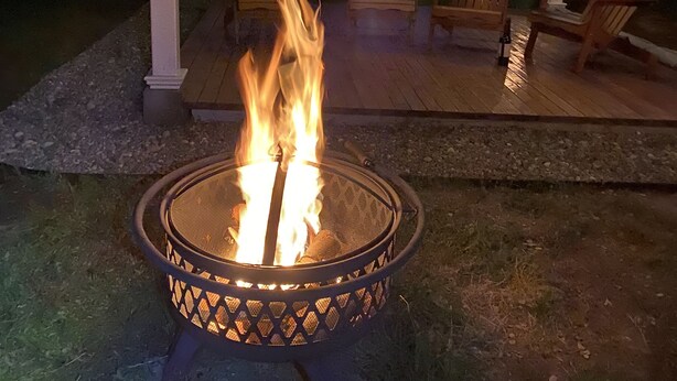A fire pit in a covered outdoor area with wooden chairs. - Cozy cottage in delightful Ahwahnee with AC, WiFi (Ahwahnee)
