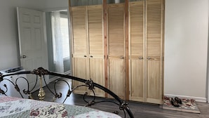 A bedroom with a wooden wardrobe, a bed with a floral bedspread, and a wooden floor. - Cozy cottage in delightful Ahwahnee with AC, WiFi (Ahwahnee)